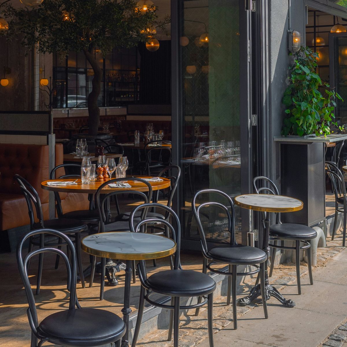 Shop front of a cafe with black tables and chairs outside
